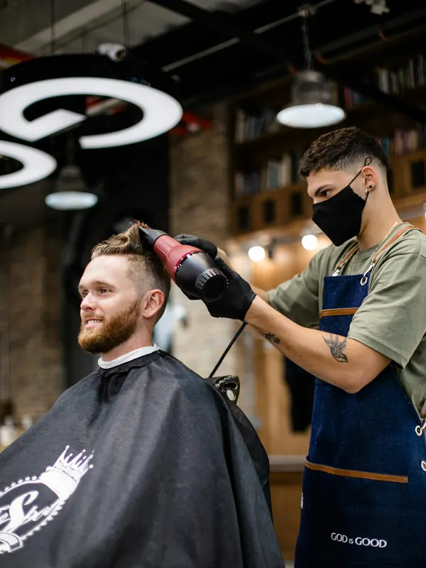 Friseur föhnt einem Mann die Haare