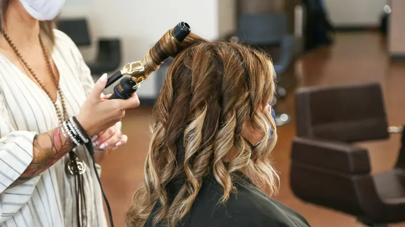 Friseurin formt Locken mit dem Lockenstab